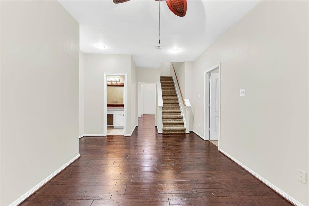3217 Royal Melbourne Drive, Plano, TX 75093 Looking across the warm wood floors, this reverse view reveals the adjoining full bathroom, staircase access, and fluid connection to the rest of the main level. It creates an inviting layout that makes entertaining, hosting sleepovers, or moving throughout the home feel completely effortless.