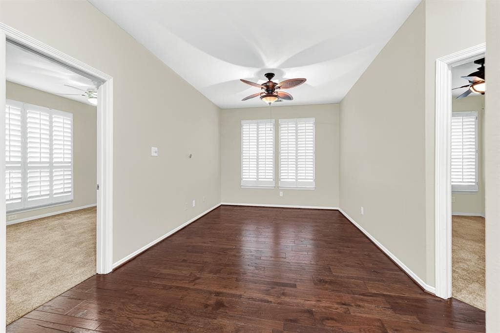 3217 Royal Melbourne Drive, Plano, TX 75093 Rich hardwood flooring grounds this central first-floor game room, framed by plantation-shuttered windows, a tropical-style ceiling fan, and direct doorways to both secondary bedrooms. It offers a convenient, shared space where kids or guests can relax, study, or hang out right near their rooms.