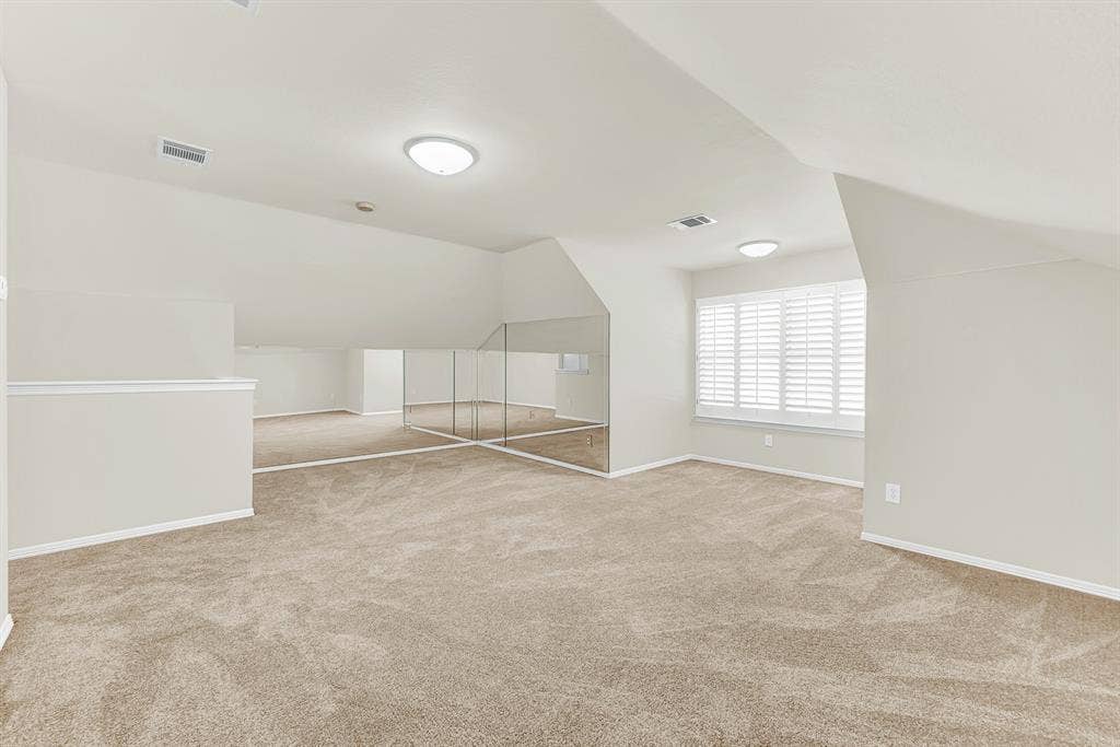 3217 Royal Melbourne Drive, Plano, TX 75093 A wide angle highlights the unique angled ceilings, expansive plush carpeting, and the mirrored wall that amplifies the natural light throughout the second floor. You will love setting up a game room or play area where kids and guests can gather for fun weekend afternoons.