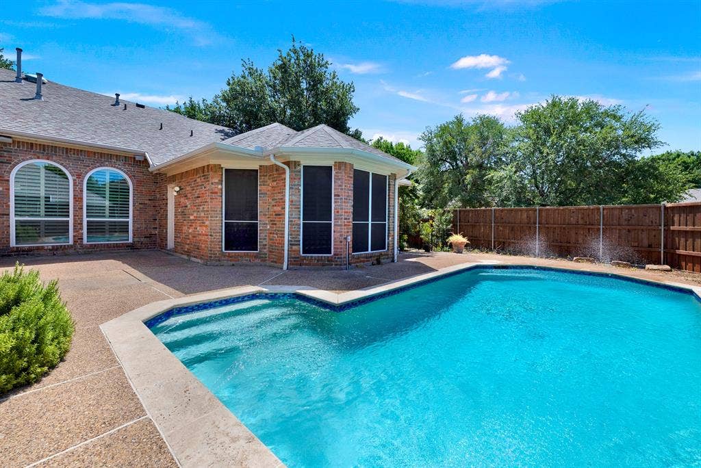 3217 Royal Melbourne Drive, Plano, TX 75093 This angle showcases the built-in pool entry steps, decorative water fountains spraying into the water, and the surrounding brick home exterior. Imagine hosting sunny weekend get-togethers with friends and family enjoying the pool while you grill out on the patio.