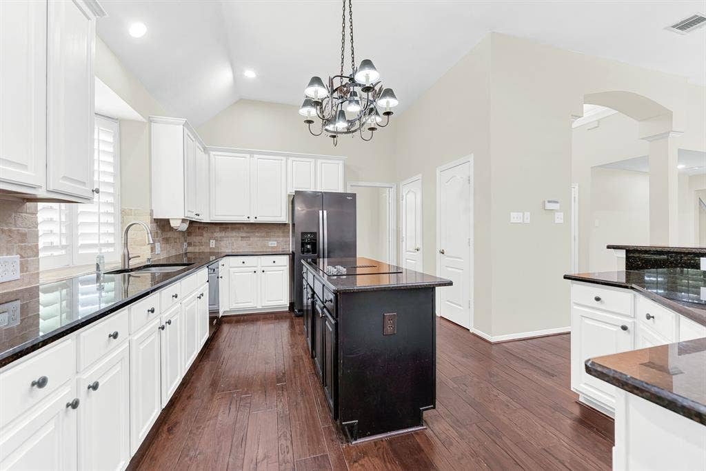 3217 Royal Melbourne Drive, Plano, TX 75093 A wide perspective down the main aisle highlights the contrast between the dark island, white surround cabinets, and the built-in double ovens. It gives home chefs plenty of room to cook together without ever feeling crowded.
