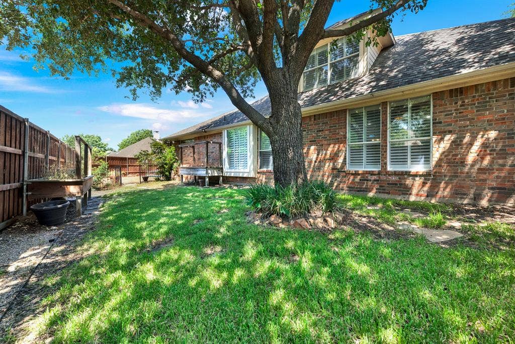 3217 Royal Melbourne Drive, Plano, TX 75093 Shaded by a grand oak tree, this lush grassy side yard features raised garden beds along a dark wood privacy fence. It offers a peaceful outdoor retreat where you can relax in the shade, tend to fresh plants, or enjoy quiet weekend mornings.