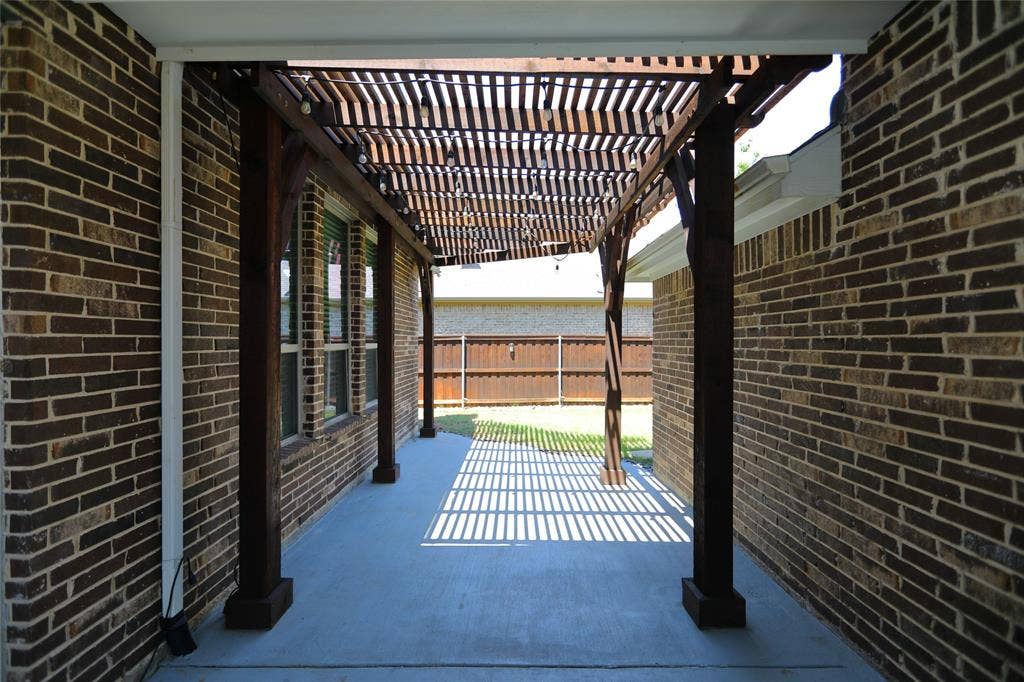 3707 Plum Vista Place, Arlington, TX 76005 Covered patio featuring a wood pergola with slatted roof, concrete flooring, and brick exterior walls