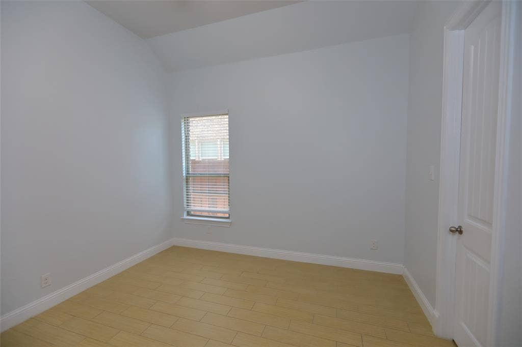 3707 Plum Vista Place, Arlington, TX 76005 Room featuring light-toned wood-finish flooring, a single window with blinds, and a white paneled door with a brass-toned knob