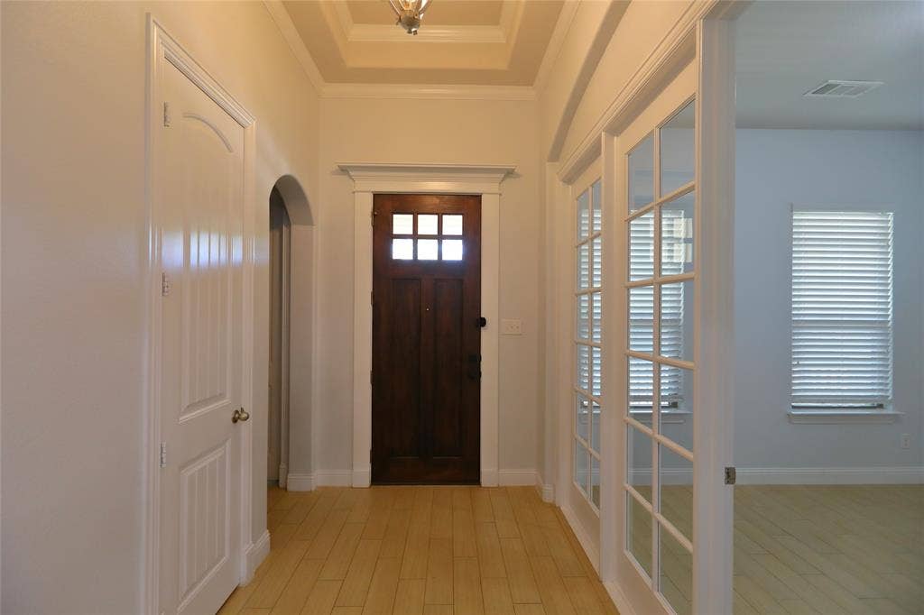 3707 Plum Vista Place, Arlington, TX 76005 Entryway featuring light wood-finish flooring, a dark wood front door with glass panes, white paneled interior doors, an arched doorway, and French doors with multiple glass lites