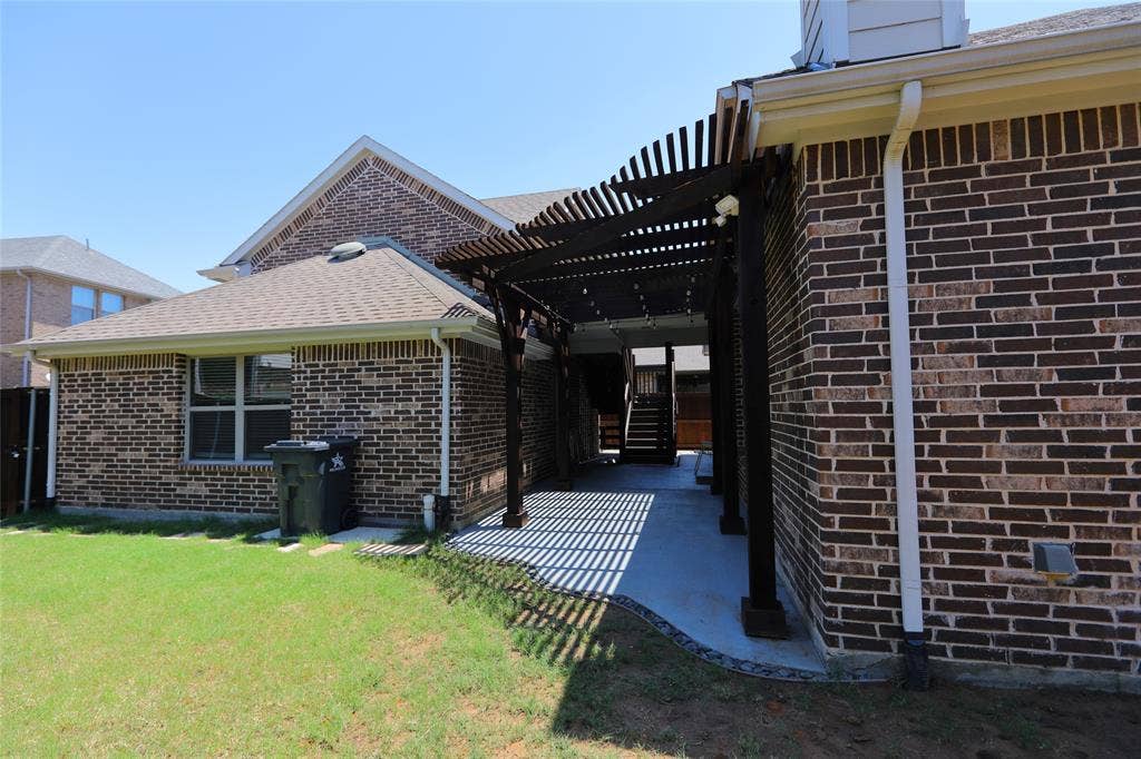 3707 Plum Vista Place, Arlington, TX 76005 Brick exterior with a covered patio featuring a dark wood pergola