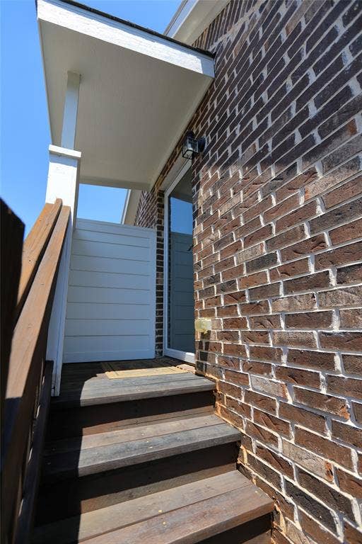 3707 Plum Vista Place, Arlington, TX 76005 Brick exterior featuring a covered entry, dark wood-finish stairs, and a white privacy wall