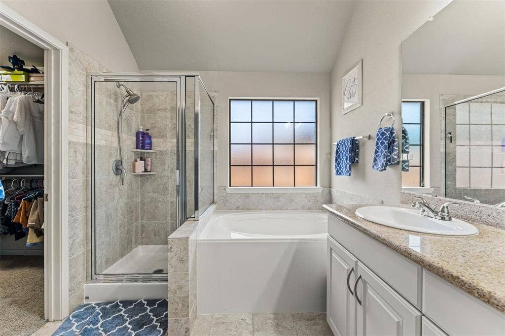 10313 Condor Loop, Waco, TX 76708 Built-in soaking tub, glass-enclosed shower with tile surround, single vanity with countertop, and framed window