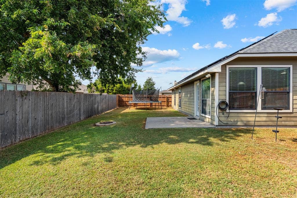 10313 Condor Loop, Waco, TX 76708 Expansive backyard with a manicured lawn, wood privacy fencing, and a concrete patio