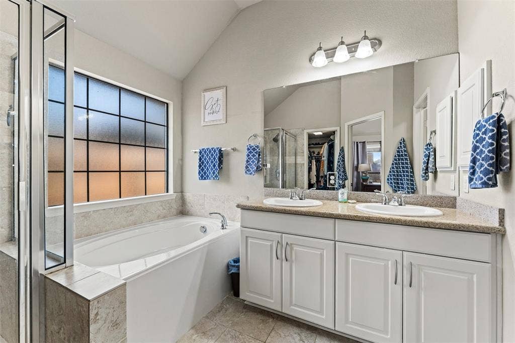 10313 Condor Loop, Waco, TX 76708 Dual vanity with undermount sinks, spacious bathtub, separate shower enclosure with glass panels, and a large privacy window