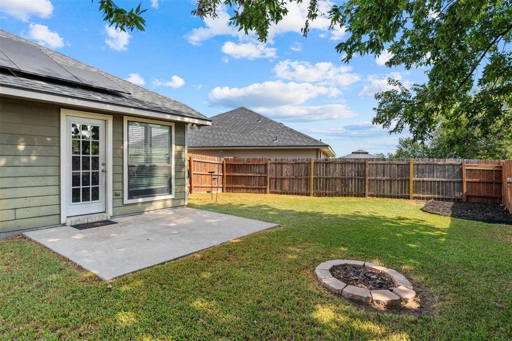 10313 Condor Loop, Waco, TX 76708 Expansive backyard featuring a concrete patio, a built-in fire pit, and wood privacy fencing