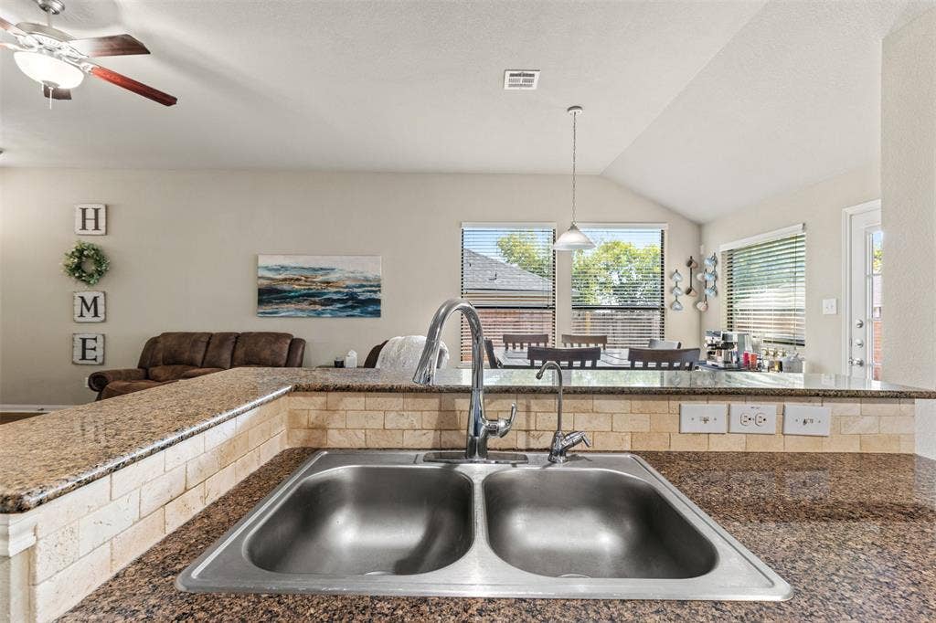 10313 Condor Loop, Waco, TX 76708 Double-basin stainless steel sink with a chrome faucet, set into a speckled countertop with a tiled backsplash