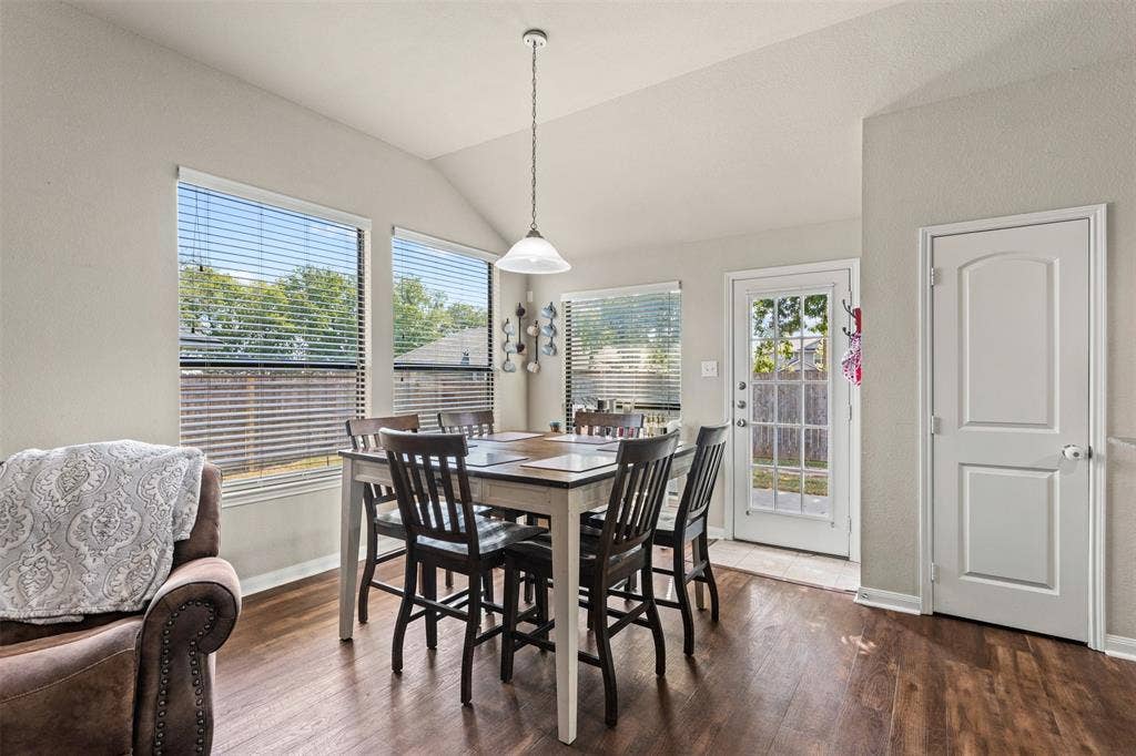 10313 Condor Loop, Waco, TX 76708 Vaulted ceiling with a pendant light fixture, wood-finish flooring, multiple windows with blinds, and a paneled door