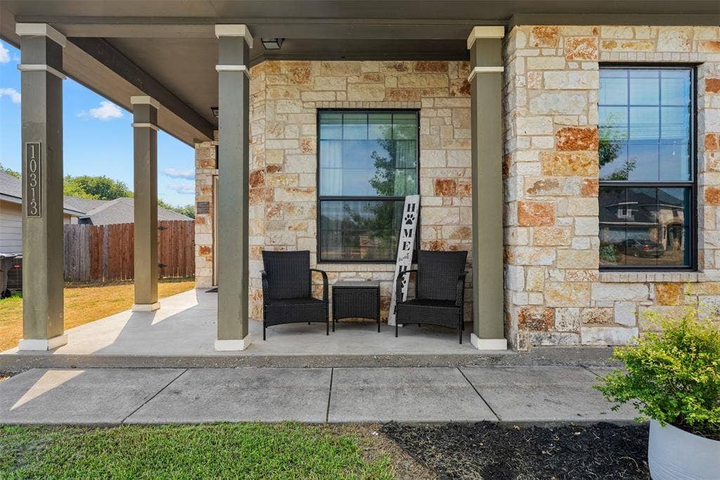 10313 Condor Loop, Waco, TX 76708 Limestone and brick veneer exterior with a covered concrete porch, multiple square columns, and dark-framed windows