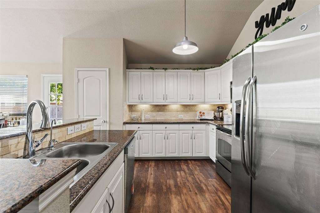 10313 Condor Loop, Waco, TX 76708 Well-appointed kitchen featuring white cabinetry, wood-finish flooring, stainless steel appliances, granite-look countertops, and an undermount sink