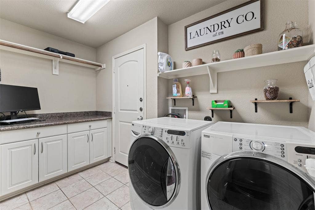 10313 Condor Loop, Waco, TX 76708 White cabinetry with dark speckled countertops, tiled flooring, and multiple wall-mounted shelves
