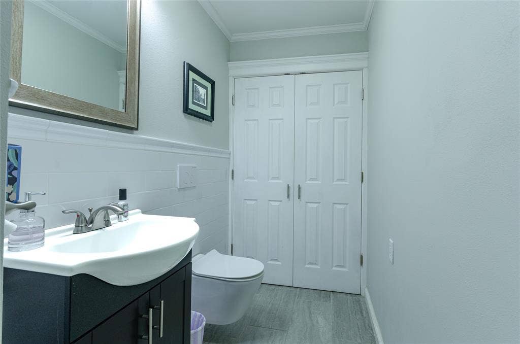 3613 Windmill Hill Street, Waco, TX 76710 Wall-mounted toilet, vanity with integrated basin, tiled wainscoting, and crown molding