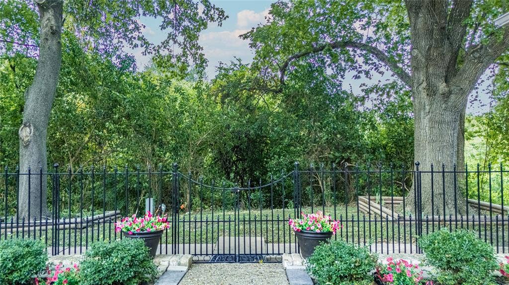 3613 Windmill Hill Street, Waco, TX 76710 Backyard with wrought iron fencing with a gated entry, mature trees, manicured shrubs, and container plantings