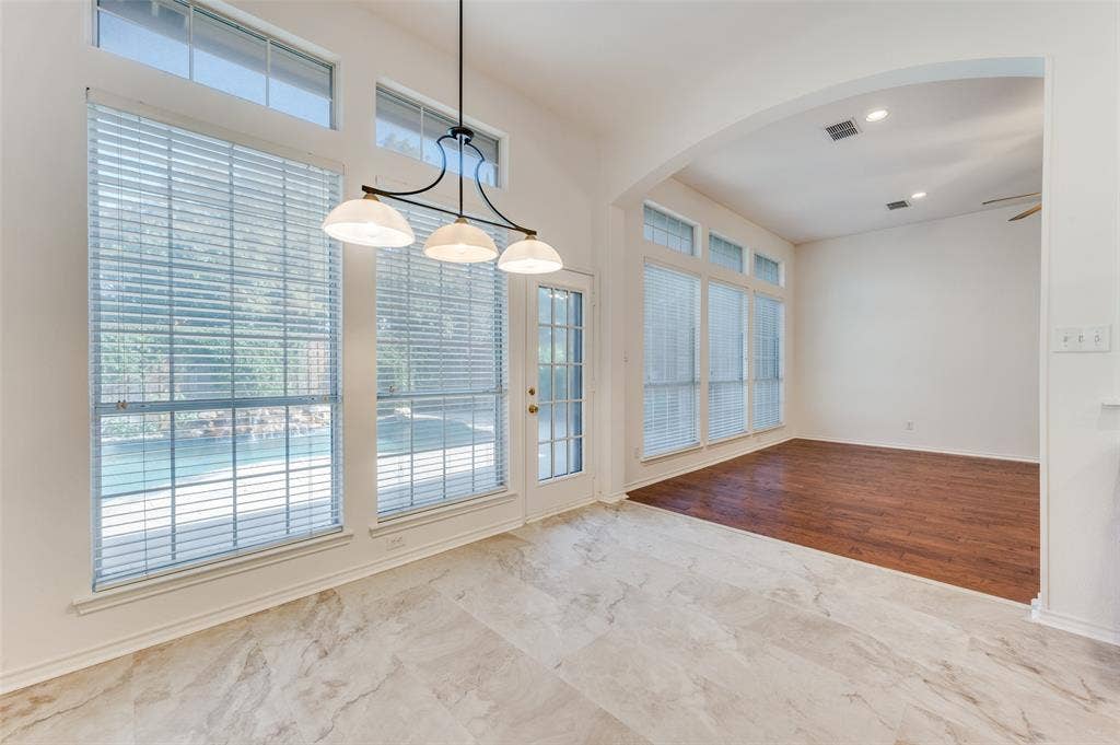 This large breakfast area, adjacent to the kitchen, features easy-to-maintain tile floors and a view of the open walkway to the den area with a fireplace.