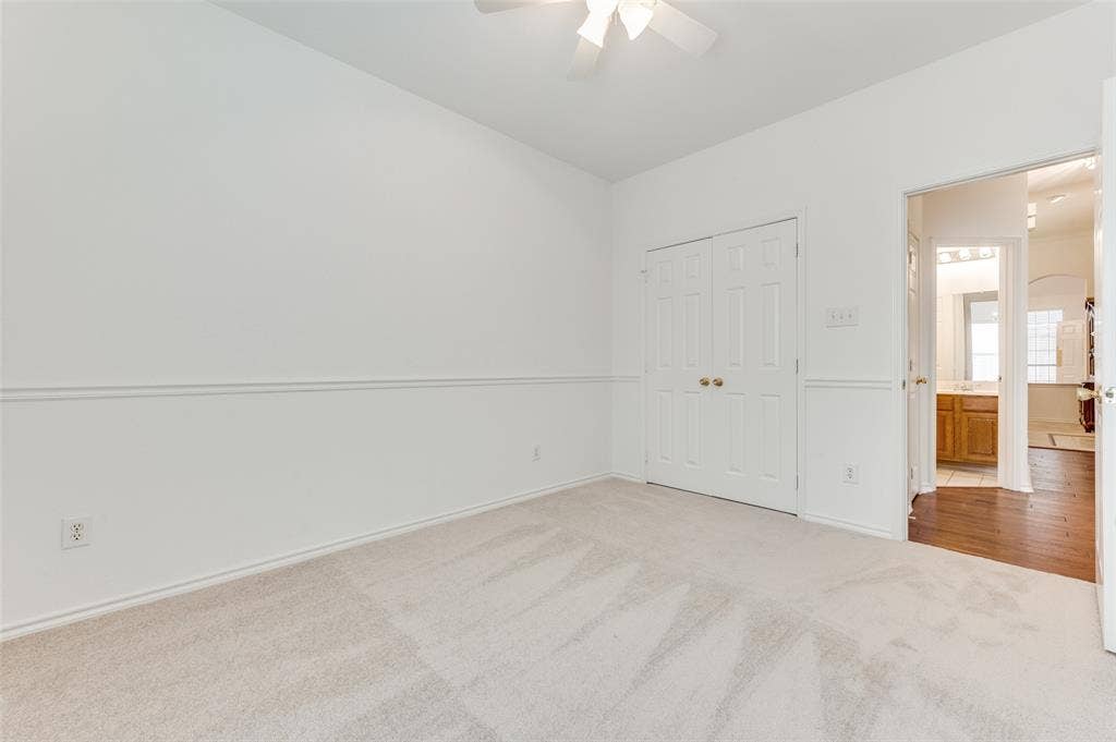 This is the 2nd bedroom located on the east side of the home.  Neutral-toned carpeting and white-painted walls with chair rail molding.  A closet is located behind the double doors on the left.