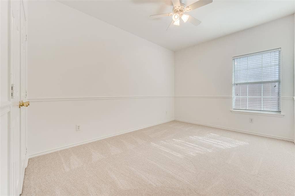 This is the 3rd bedroom, located on the east side of the home.  Vaulted ceiling, ceiling fan, neutral carpet flooring, single window with blinds, and white paneled doors