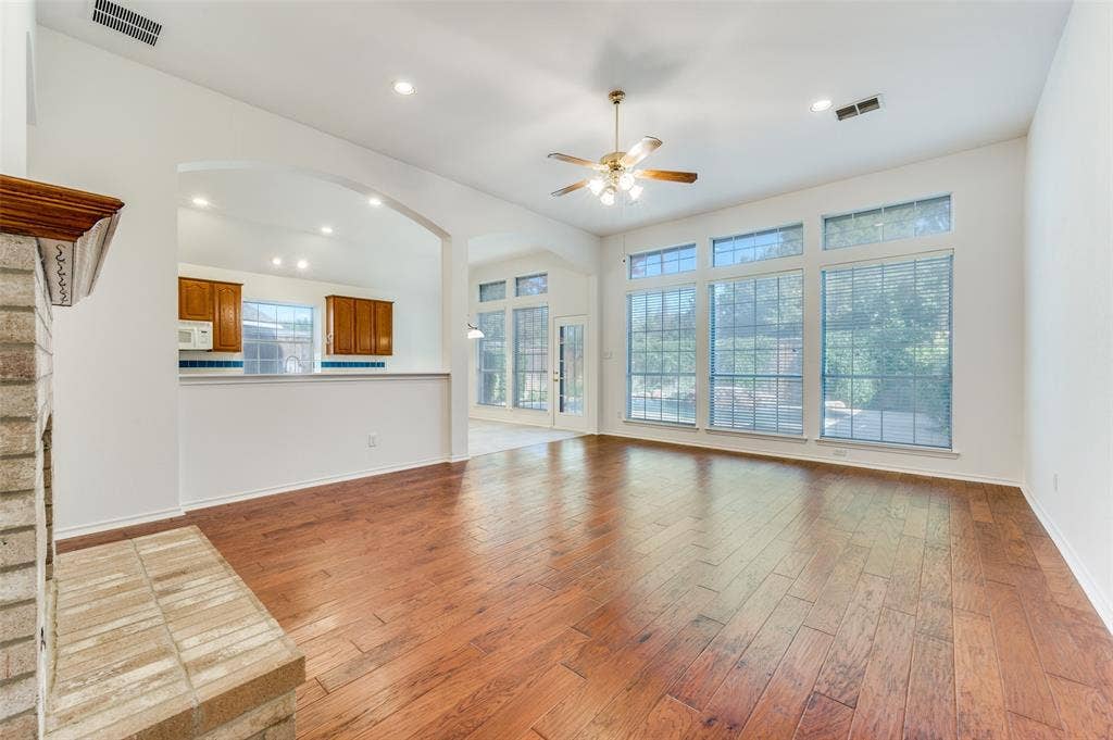 Wood flooring, vaulted ceiling with a ceiling fan & light, stone-clad fireplace, large windows with horizontal blinds, and recessed lighting.  The great view of the backyard and pool makes this the perfect place to lounge.