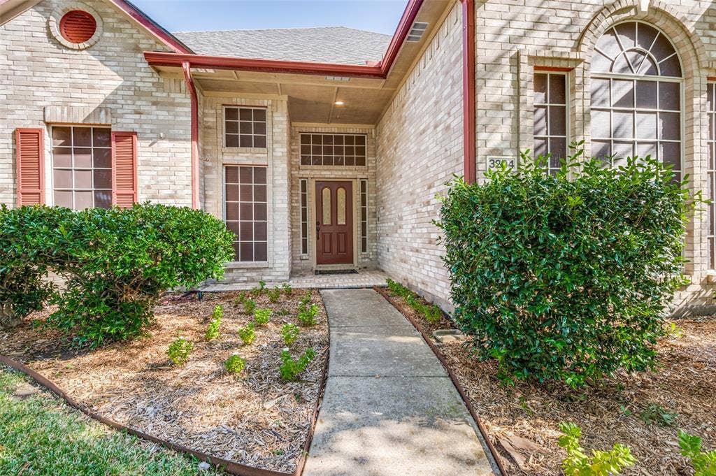 Brick exterior with red-toned gutters and trim.  Lots of flowerbeds for a person with a green thumb!