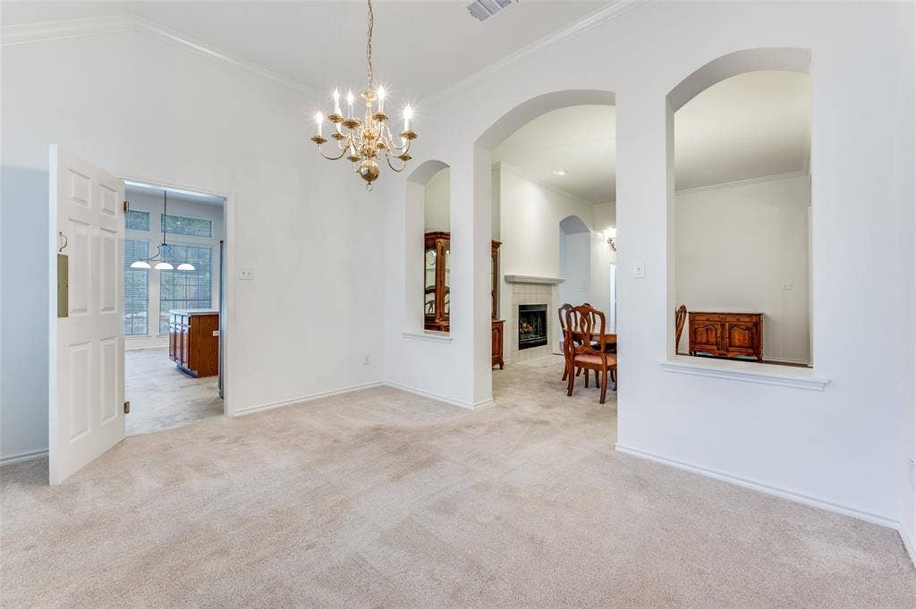 Formal dining room with a chandelier adjacent to a living room or sitting room with a double-sided fireplace.