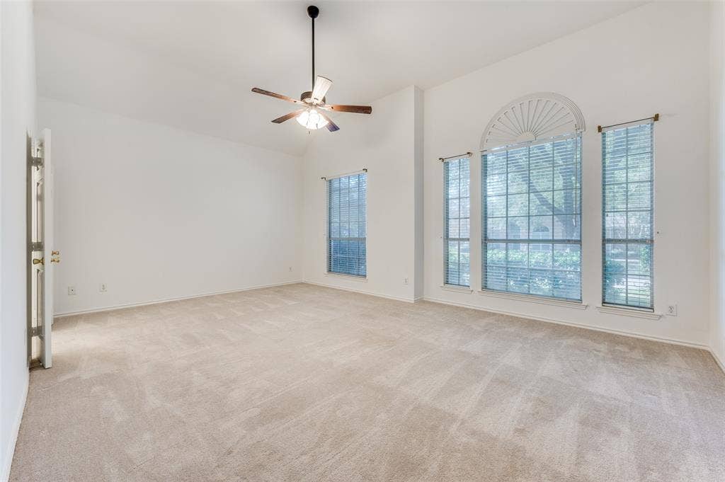 Huge primary bedroom with high ceilings and a fan with a light kit.  Super large room.  The door on the left leads to the large primary bathroom.