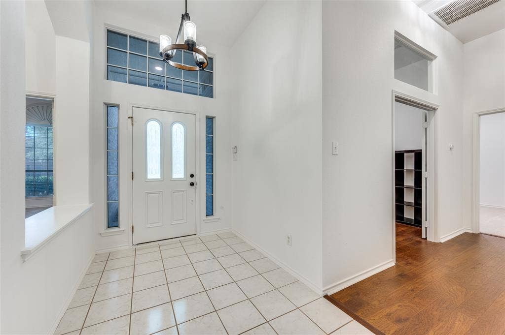 Two-story foyer featuring a white paneled entry door, sidelight windows, and a transom window.  Office just to the left by engineered wood flooring.