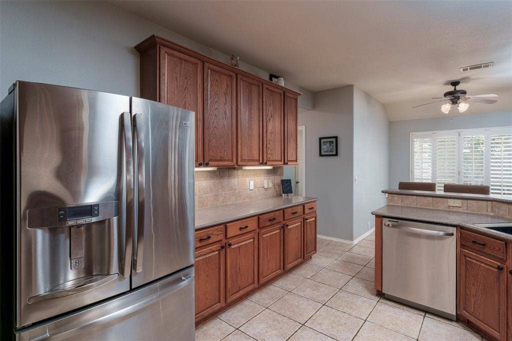 1620 Babbling Brook Drive, Grand Prairie, TX 75050 Kitchen featuring stainless steel appliances, wood cabinetry, tile flooring, and a ceiling fan