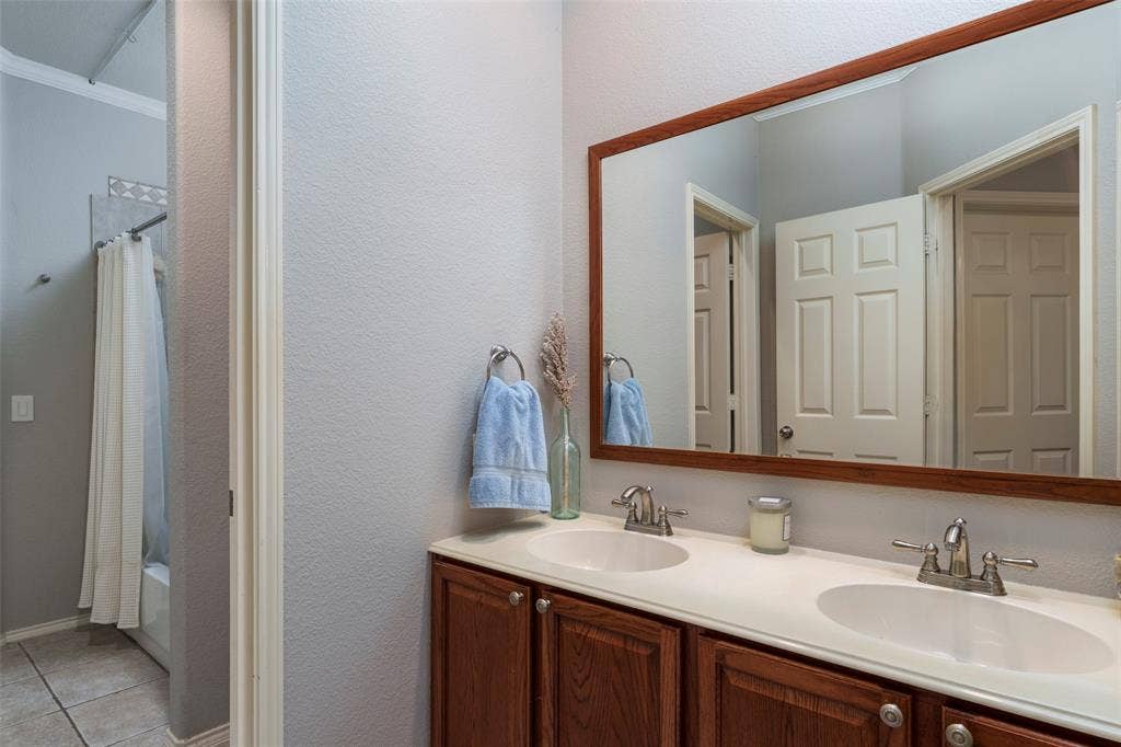 1620 Babbling Brook Drive, Grand Prairie, TX 75050 Dual vanity with integrated sinks, wood-finish cabinetry, and a framed mirror