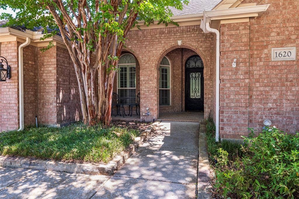 1620 Babbling Brook Drive, Grand Prairie, TX 75050 Brick exterior with arched entryways, a decorative glass front door, and a concrete pathway