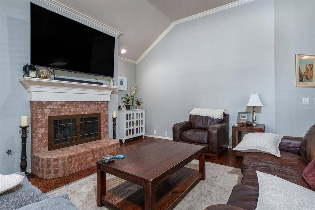 1620 Babbling Brook Drive, Grand Prairie, TX 75050 Brick fireplace with a substantial mantel, wood-finish flooring, and a vaulted ceiling
