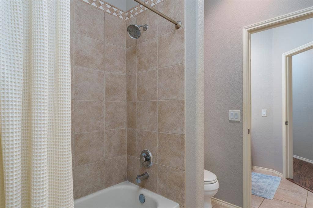 1620 Babbling Brook Drive, Grand Prairie, TX 75050 Bathtub with tiled surround, decorative tile accent, and brushed nickel fixtures