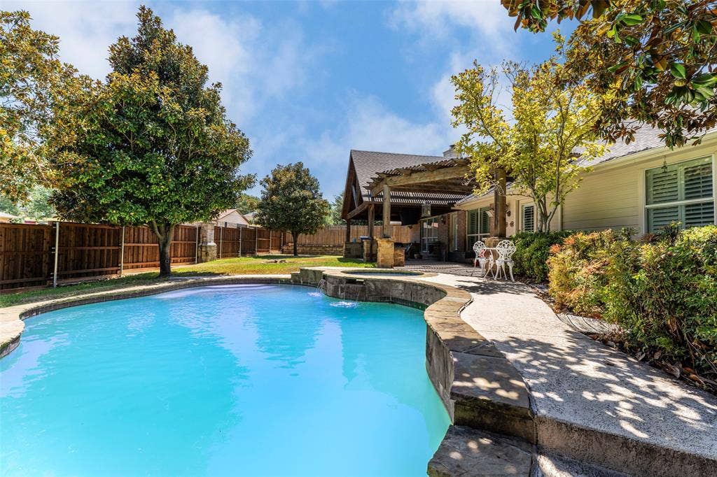 1620 Babbling Brook Drive, Grand Prairie, TX 75050 Curved swimming pool with stone coping, an integrated spa, and a water feature