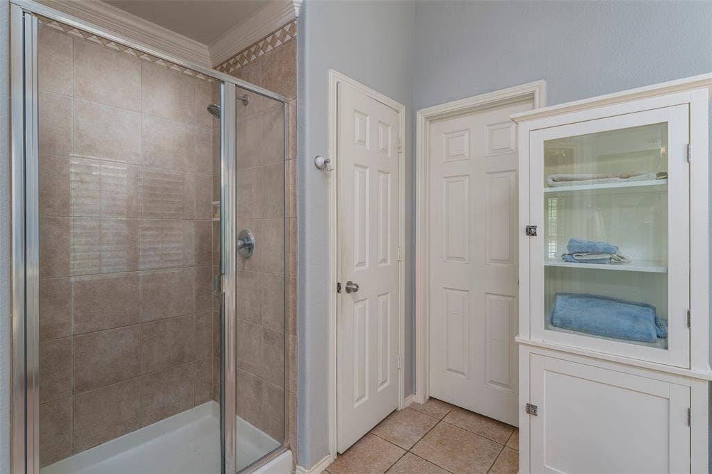 1620 Babbling Brook Drive, Grand Prairie, TX 75050 Glass-enclosed shower with tile surround, crown molding, and tiled flooring