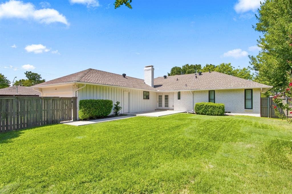 1409 Navaho Trail, Richardson, TX 75080 Expansive green lawn with a white brick exterior, light brown shingle roof, and a privacy fence