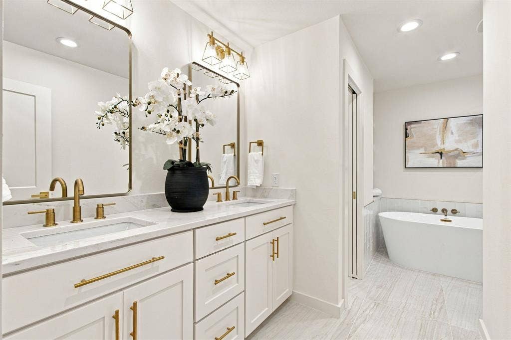 1409 Navaho Trail, Richardson, TX 75080 Dual vanity with undermount sinks, white cabinetry, and gold-finish hardware