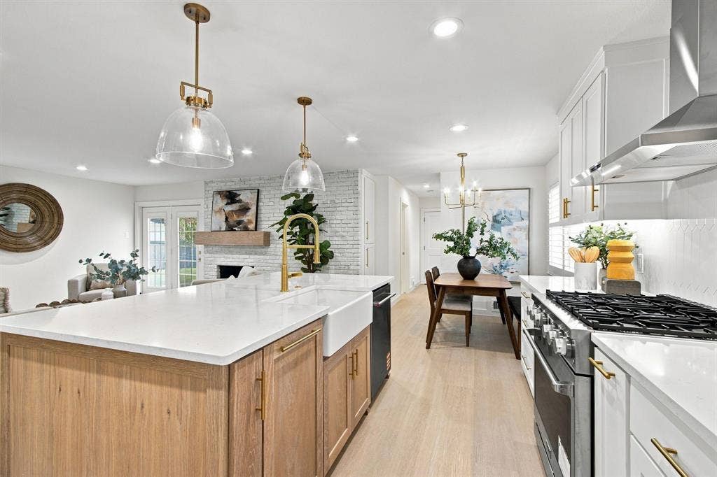 1409 Navaho Trail, Richardson, TX 75080 Open-concept kitchen with a large central island, white shaker cabinetry, stainless steel appliances, and wood-finish flooring