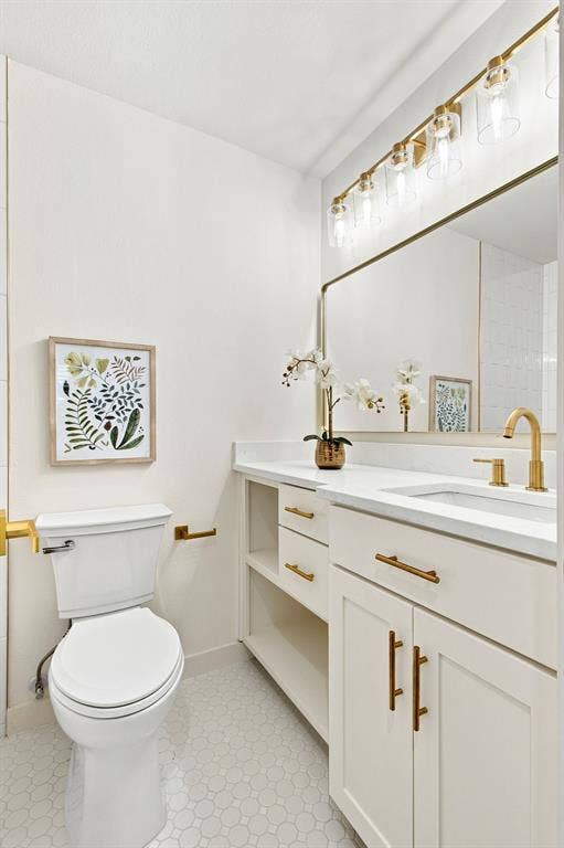 1409 Navaho Trail, Richardson, TX 75080 White vanity with a single integrated sink, gold-finish faucet, and coordinating hardware