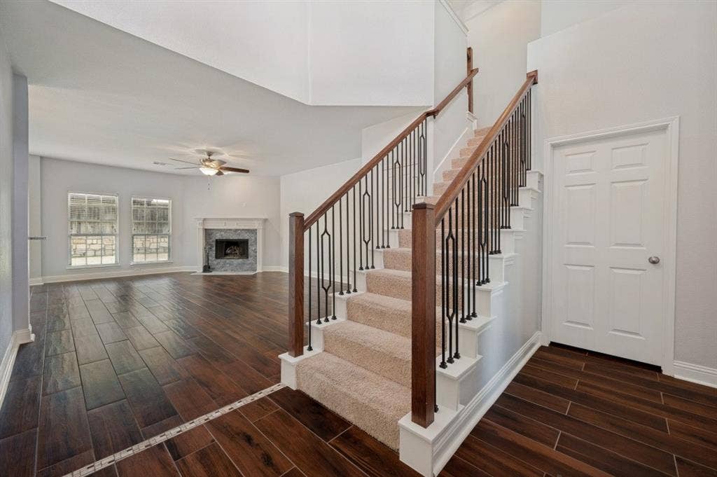 7900 White Stallion Trail, McKinney, TX 75070 Expansive living area with wood-finish flooring, a ceiling fan, and a fireplace with a light-colored mantel