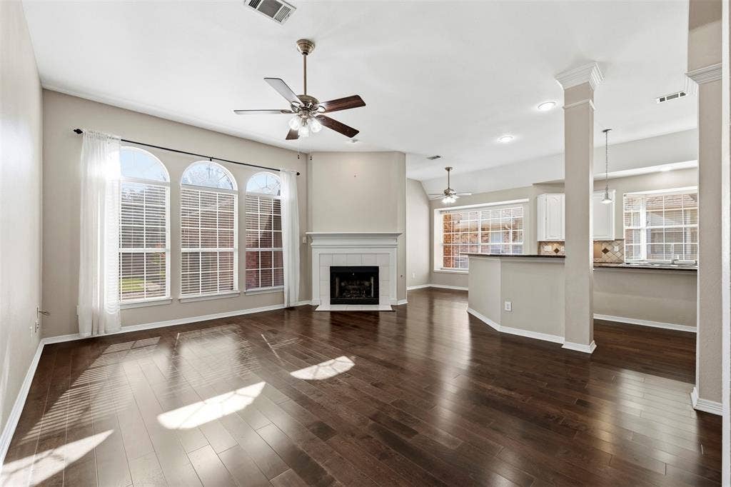 2910 Live Oak Drive, Rowlett, TX 75088 Spacious living area featuring wood-finish flooring, a fireplace with a white mantel, and arched windows