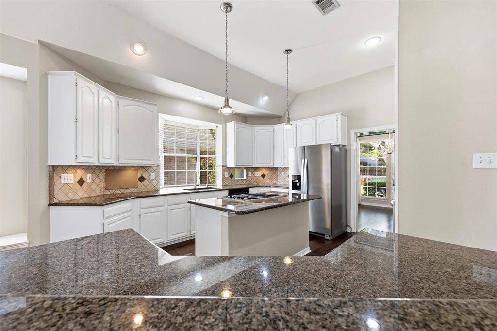 2910 Live Oak Drive, Rowlett, TX 75088 Kitchen featuring white cabinetry, granite countertops, tile backsplash, and stainless steel appliances