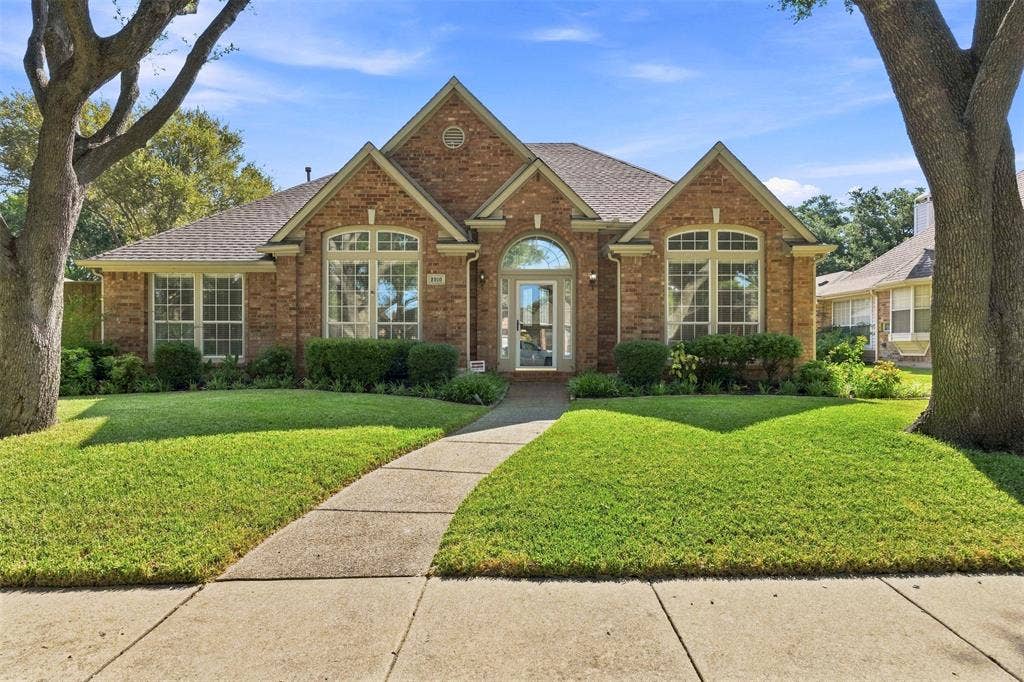 2910 Live Oak Drive, Rowlett, TX 75088 Elegant brick Colonial estate showcasing arched entryways, multi-pane windows with decorative pediments, and a welcoming covered entry portico