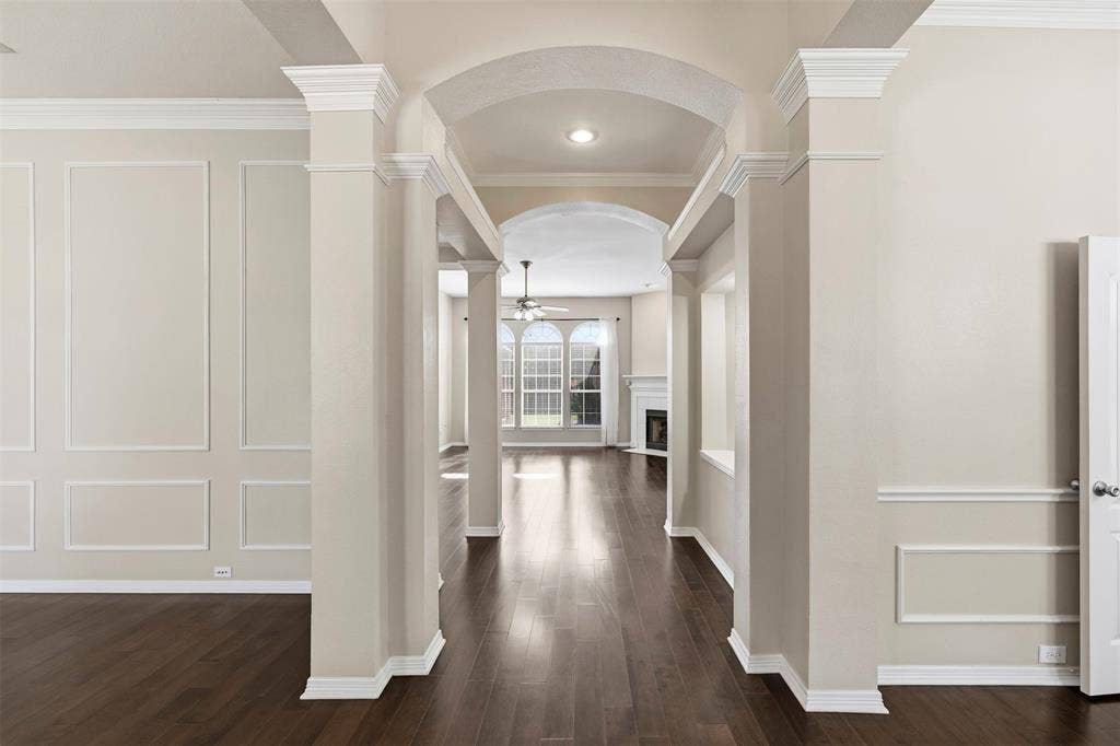 2910 Live Oak Drive, Rowlett, TX 75088 Arched entryway with substantial columns, dark wood-finish flooring, and decorative wall paneling