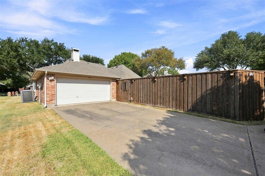 2910 Live Oak Drive, Rowlett, TX 75088 Attached two-car garage with a concrete driveway, brick exterior, and a wood privacy fence