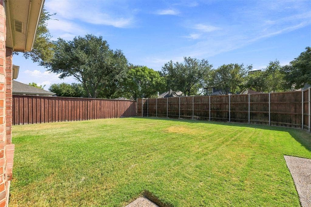 2910 Live Oak Drive, Rowlett, TX 75088 Expansive backyard featuring a manicured lawn, wood privacy fencing, and a concrete patio