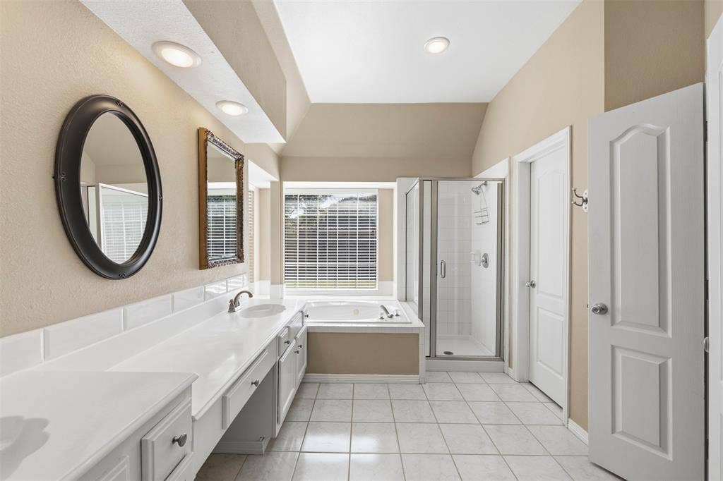 2910 Live Oak Drive, Rowlett, TX 75088 Dual vanity with integrated sinks, built-in soaking tub, glass-enclosed shower, tiled flooring, and recessed lighting
