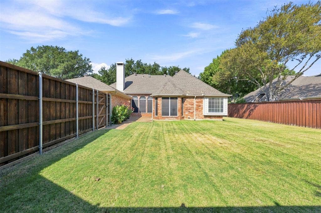 2910 Live Oak Drive, Rowlett, TX 75088 Expansive backyard featuring a manicured lawn, brick exterior, bay window, and privacy fencing